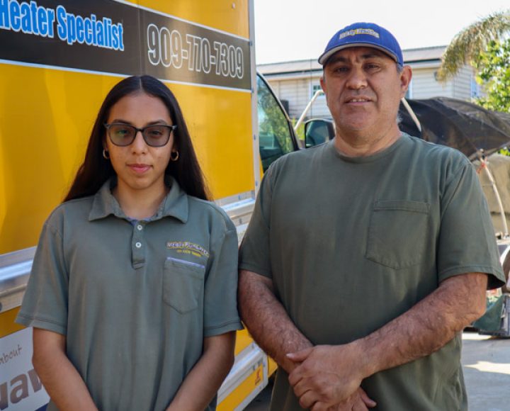 A father and his daughter standing in front of their plumbing service vehicle, representing the family-owned nature of their business.
