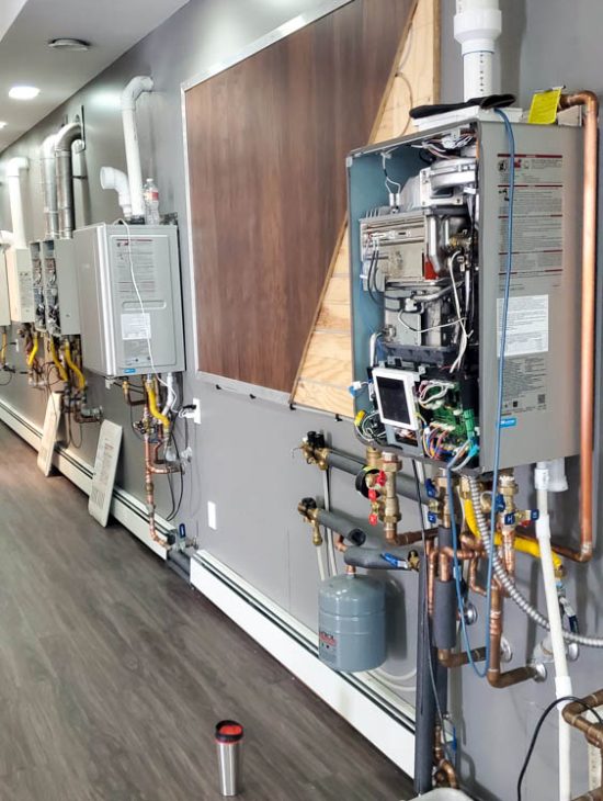 Efficient Water Heating System Setup A series of tankless water heaters installed along a wall in a commercial setting, each with detailed pipework and controls.