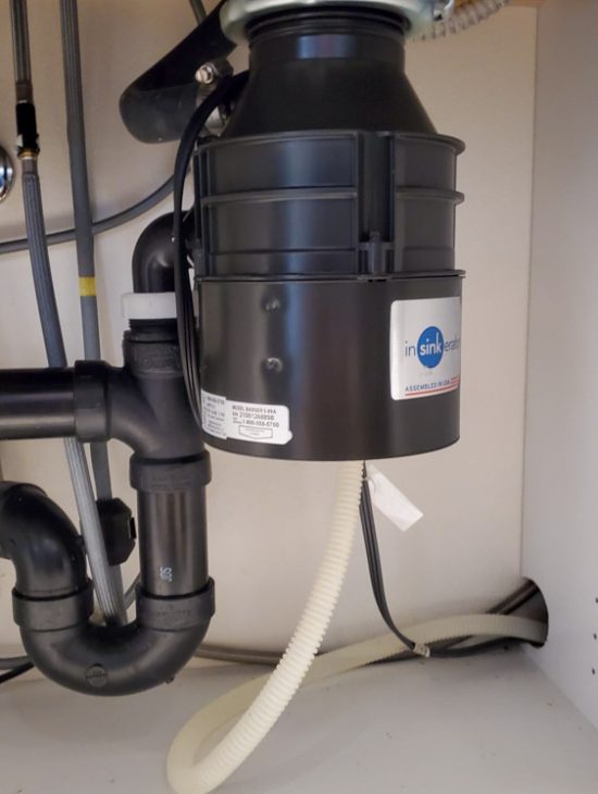 Compact Garbage Disposal System Compact black InSinkErator garbage disposal installed under a sink, neatly integrated with the kitchen plumbing.