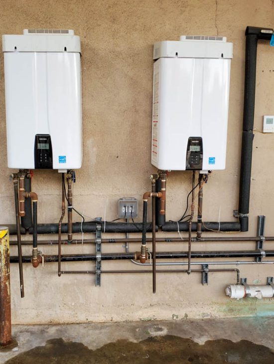 Dual Tankless Water Heaters Installation Two high-capacity tankless water heaters installed on a wall, efficiently set up with multiple copper pipes and digital temperature controls.