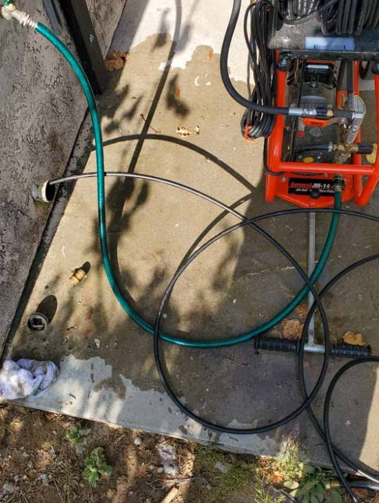 Advanced Drain Cleaning Setup A professional drain cleaning machine with attached hoses and nozzles, ready for operation next to a residential building.